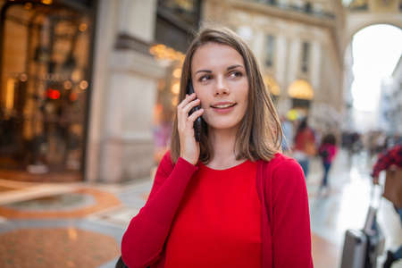Young woman talking on the phone while walking in an european cityの写真素材