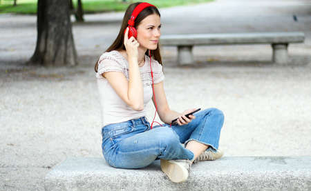 Woman listening to music sitting ona bench in a parkの写真素材