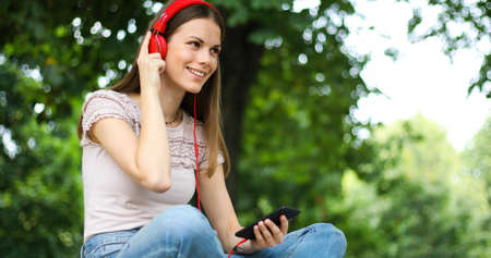 Woman listening to music sitting ona bench in a parkの写真素材