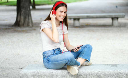 Woman listening to music sitting ona bench in a parkの写真素材