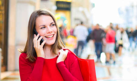 Young woman shopping with a Christmas outfit while walking and speaking on the phoneの写真素材