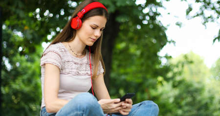 Woman listening to music sitting ona bench in a parkの写真素材