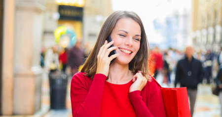 Young woman shopping with a Christmas outfit while walking and speaking on the phoneの写真素材