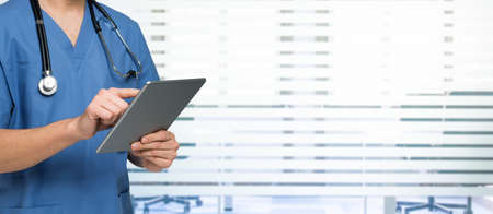 Detail of a doctor using a tablet. Wide image with large copy-spaceの写真素材