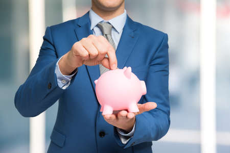 Man putting money in a piggy bankの写真素材