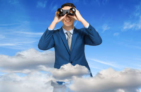 Businessman looking through binocularsの写真素材