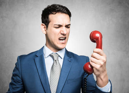 Angry businessman yelling on the phone. Grunge backgroundの写真素材
