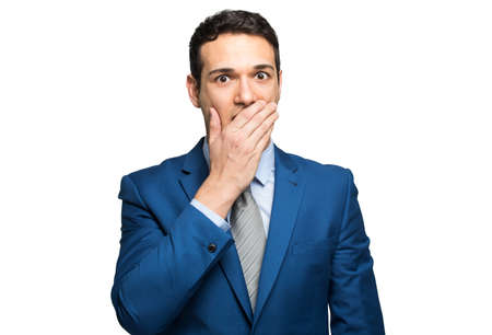 Funny businessman is covering his mouth with hands. Isolated on white background.の写真素材