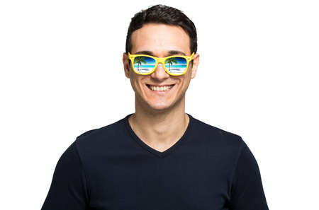Young man wearing glasses in which there's a beautiful sea landscape reflected into themの写真素材