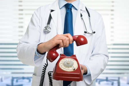 Doctor holding a vintage phone, medical contact and communication conceptの写真素材