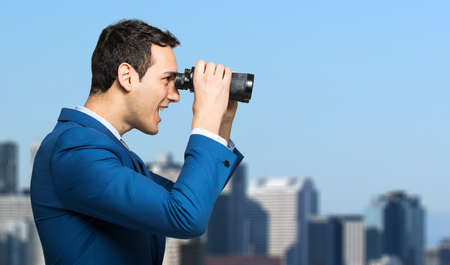 Businessman looking through binocularsの写真素材
