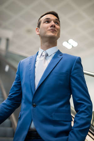 Businessman holding a trolley in an airport on an escalatorの写真素材