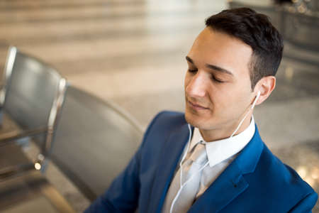 Man listening to music while waiting in an airportの写真素材