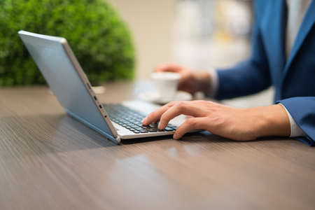 Detail of a businessman using a netbook in a cafeの写真素材