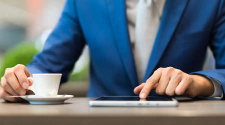 Businessman having breakfast and reading his tabletの写真素材
