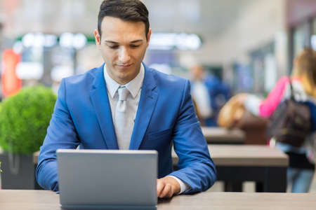 Businessman working on laptop computer at airportの写真素材