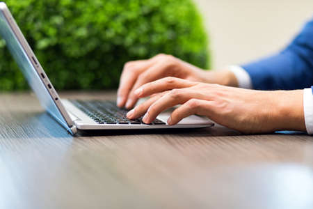 Closeup of a man typing on a laptop keyboardの写真素材