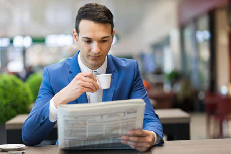 Young manager having a coffee and reading a newspaperの写真素材