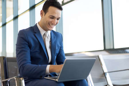 Young businessman working with his laptop in an airportの写真素材