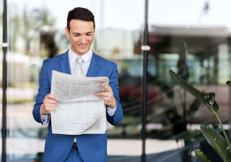Handsome businessman in suit reading newspaperの写真素材
