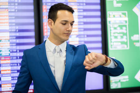 Businessman checking time in the airport, flight delay conceptの写真素材