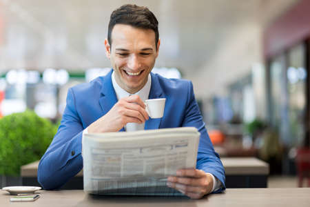 Young manager having a coffee and reading a newspaperの写真素材