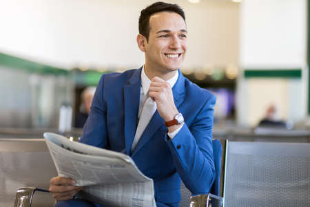 Professional handsome businessman reading a newspaper and resting while sitting in the departure loungeの写真素材