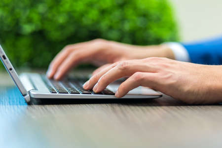 Closeup of a man typing on a laptop keyboardの写真素材