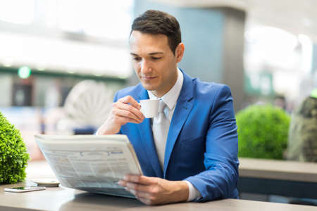Young manager having a coffee and reading a newspaperの写真素材