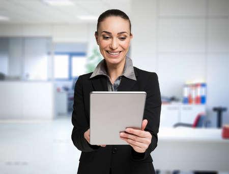 Smiling business woman using a tablet in her officeの写真素材