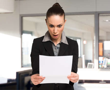 Surprised woman reading a business document in her officeの写真素材