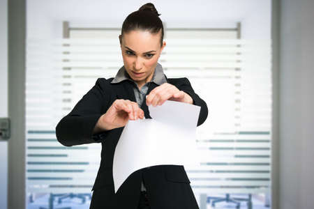 Angry woman tearing a contract apart in her office