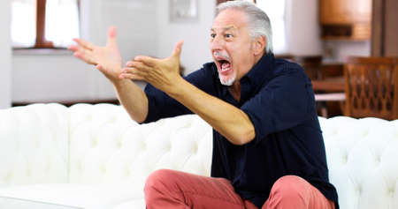 Senor guy watching sports on tv and shoutingの写真素材