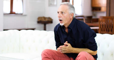 Senor guy watching sports on tv and shoutingの写真素材
