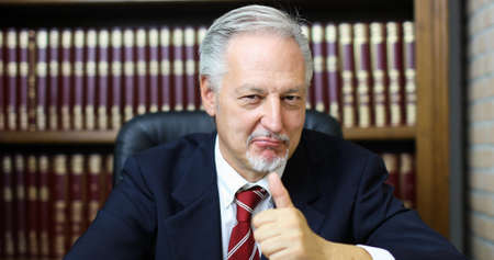 Portrait of smiling senior businessman in his libraryの写真素材