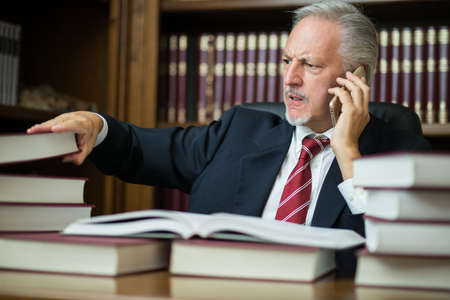 Businessman taking a book while talking on the phoneの写真素材