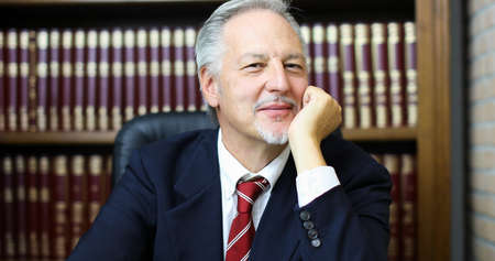 Portrait of smiling senior businessman in his libraryの写真素材