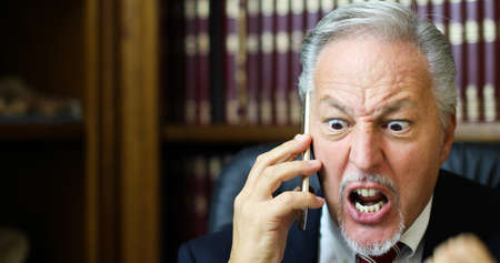 Angryman in office answering the phoneの写真素材
