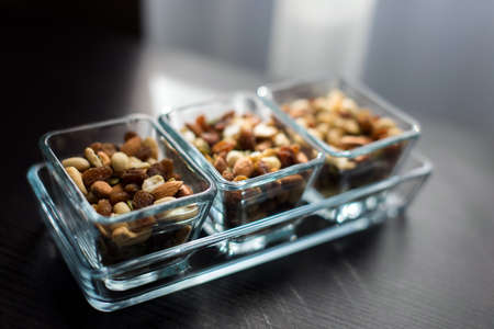 Raisins, peanuts and pistachio in elegant glass bowlsの写真素材