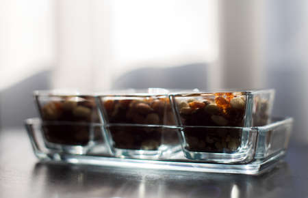 Raisins, peanuts and pistachio in elegant glass bowlsの写真素材