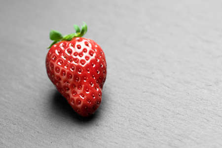 Juicy strawberry lying on a dark surfaceの写真素材