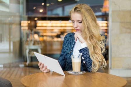 Young businesswoman on a coffee break. Using tablet computer.