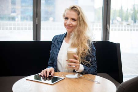 Young businesswoman on a coffee break. Using tablet computer.の写真素材