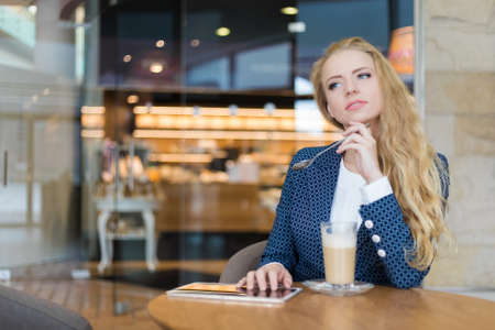 Young businesswoman on a coffee break. Using tablet computer.の写真素材