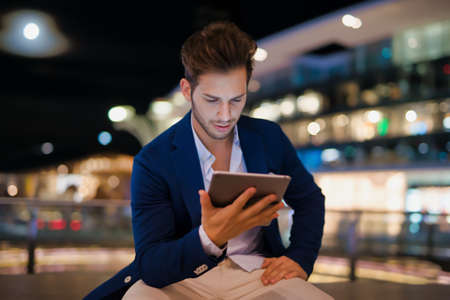 Portrait of man using his tablet in a city at nightの写真素材