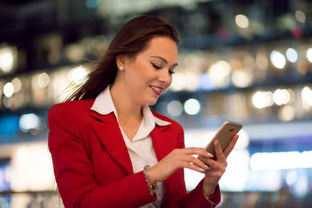 Woman using her cellphone at night in a cityの写真素材
