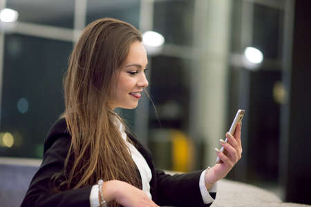 Woman using her cellphone at night in a cityの写真素材