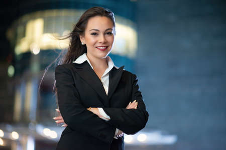 Young businesswoman portrait in a modern city setting at nightの写真素材