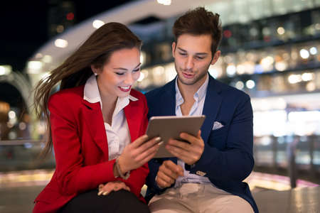 People using tablet at night in a cityの写真素材