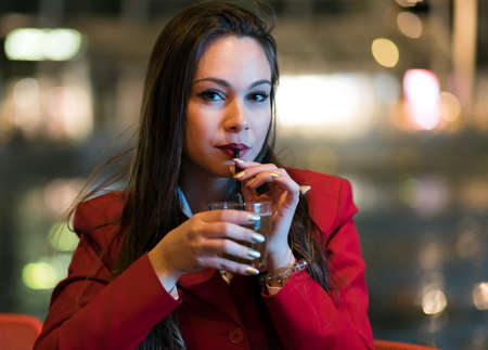 Young woman holding a drink at a night club outdoorの写真素材